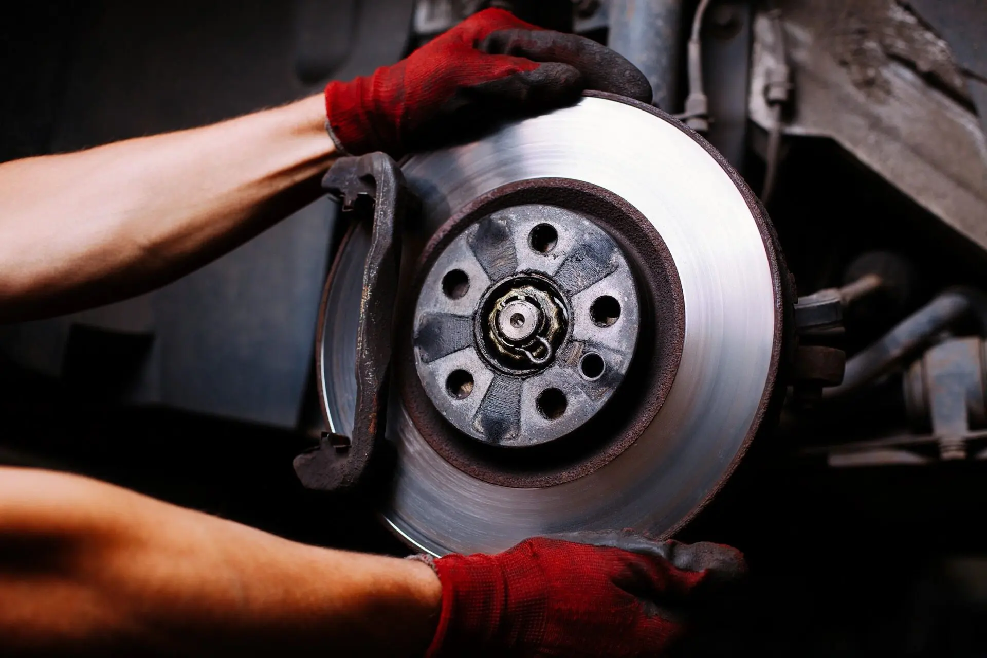 A person with red gloves is holding the brake disc.